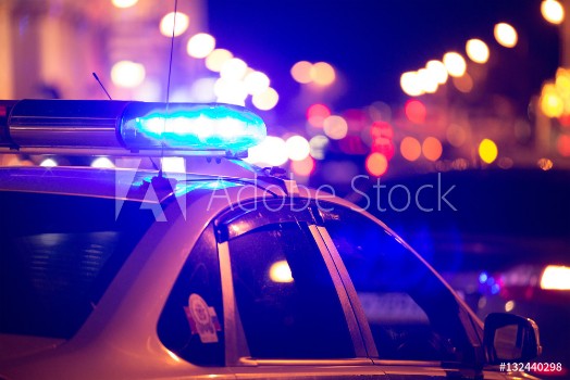 Picture of Blue light flasher atop of a police car City lights on the background